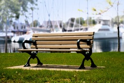Wooden Park Bench Beside A Marina With Boats In The Background