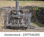 Wooden part of an old sugarcane windmill at the Estate Mount Washington in St. Croix.  Ruins of the plantation are in the background, along with grass.