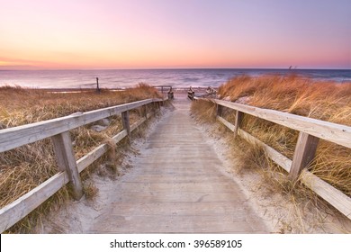Wooden path at Baltic sea over sand dunes with ocean view, sunset summer evening   