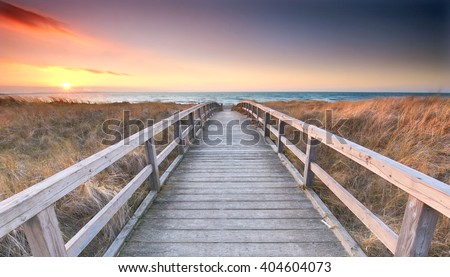 Wooden path at Baltic sea over sand dunes with ocean view, sunset summer evening                              