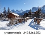 Wooden Pedestrian Footbridge Spring Creek Mountain Village, Canmore Alberta. Distant Snow Covered Three Sisters Canadian Rocky Mountain Peaks Skyline