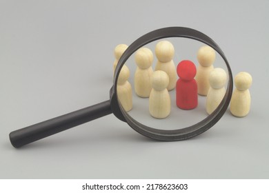 Wooden People Figures Under Magnifying Glass, One Figure Is Red As Employer With Skills. Hire Workers And Find Talents Concept.