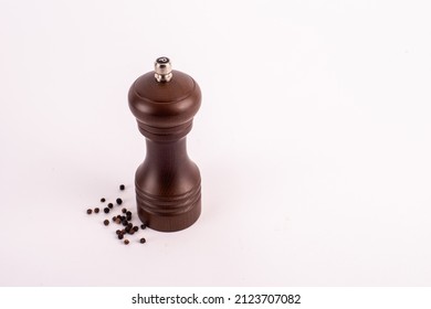 Wooden Pepper Grinder With Pepper On White Background.