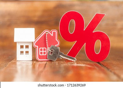 Wooden Percent Sign And  Model House With Key On Wooden Background . Real Estate Concept