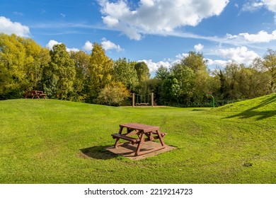 Wooden Picnic Bench In Colourful Public Park With Bright Blue Sky.