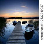 Wooden Pier at calm lake with boats at sunset