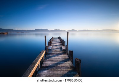 Wooden pier or jetty and lake at sunrise. Torre del Lago Puccini, Versilia, Massaciuccoli lake, Tuscany, Italy, Europe