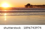 Wooden pier on piles, silhouette at sunset, California USA, Oceanside. Waterfront resort, pacific ocean tide, tropical beach. Summertime coastline vacations atmosphere. Sunny sea waves at sundown.