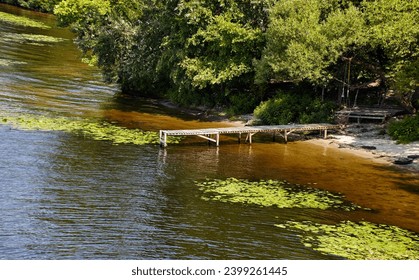 Wooden pier on the river bank. Ripple on the water surface. Blurred image, selective focus - Powered by Shutterstock