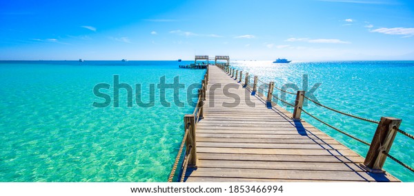 Wooden Pier at Orange Bay Beach with crystal\
clear azure water and white beach - paradise coastline of Giftun\
island, Mahmya, Hurghada, Red Sea,\
Egypt.