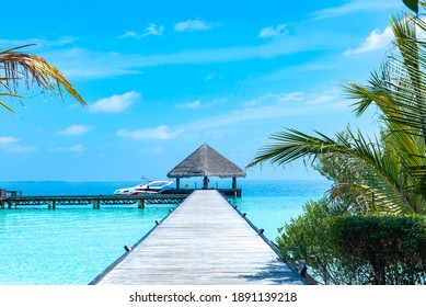 Wooden Pier In The Sea At Day Time With Blue Sky And Beautiful Clouds In The Maldives, The Concept Of Luxury Travel