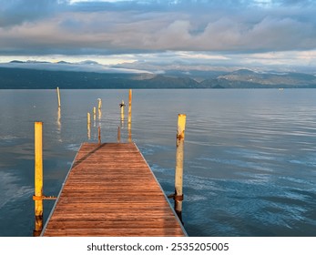 Wooden pier at sunrise on calm waters of Skadar lake near Shkoder town in Albania. Panoramic view of Dinaric Alps mountains, Southern Montenegro. Serene lakeside scene. Summer vacation. Tranquility - Powered by Shutterstock