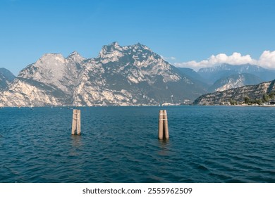 Wooden piers in idyllic Lake Garda seen from lakeside town Nago-Torbole, Trentino, Northern Italy. Majestic steep rugged cliffs and mountain peaks of Garda Prealps. Travel destination in summer - Powered by Shutterstock