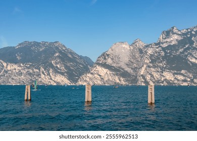 Wooden piers in idyllic Lake Garda seen from lakeside town Nago-Torbole, Trentino, Northern Italy. Majestic steep rugged cliffs and mountain peaks of Garda Prealps. Travel destination in summer - Powered by Shutterstock