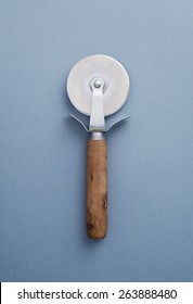 Wooden pizza slicer over blue background, above view