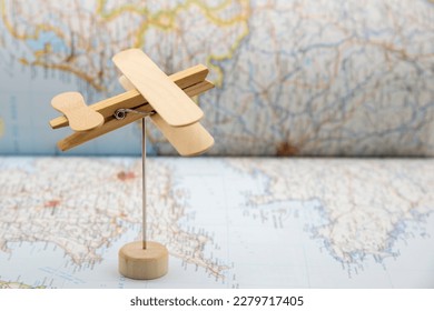 Wooden plane made with ice cream sticks and a clothespin, flying over a map