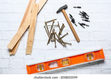 Wooden Plank, Building Level Tool, Hammer, Screws And Bolts On White Brick Background