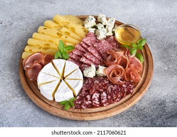 Wooden plate with delicacies. Brie cheese, blue cheese, salami, prosciutto on a wooden board. - Shutterstock ID 2117060621
