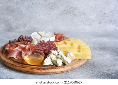 Wooden plate with delicacies. Brie cheese, blue cheese, salami, prosciutto on a wooden board. - Powered by Shutterstock