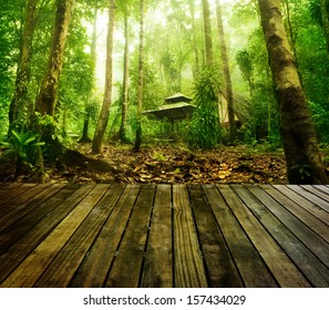 Wooden platform and green forest and huts in a misty morning, Malaysia.