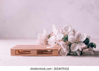 Wooden Podium In Form Of Pallet On Light Plaster Surface With Apple Flowers. Podium, Pedestal Or Stage. Mockup For Cosmetic Products