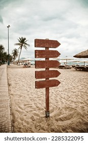 Wooden pointer post with copy space at the beach. Blank arrows on a guidepost pointing at the sea. Signpost showing the way to the beach facilities