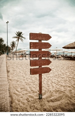 Wooden pointer post with copy space at the beach. Blank arrows on a guidepost pointing at the sea. Signpost showing the way to the beach facilities
