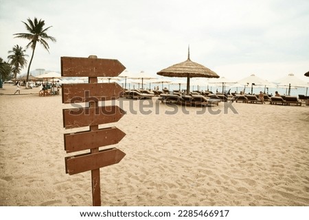 Wooden pointer post with copy space at the beach. Blank arrows on a guidepost pointing at the sea. Signpost showing the way to the beach facilities