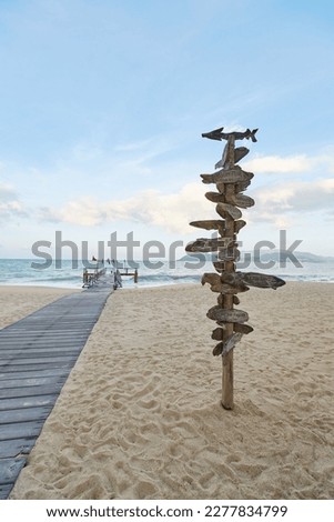 A wooden pole with pointers and arrows to indicate a landmark on the city beach. High quality photo