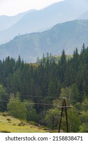 Wooden poles with electrical wires in mountainous region. Spread of electricity to hard-to-reach areas. Old electrification technologies of last century