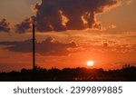 wooden poles with power lines against the background of clouds and the evening setting sun on an orange sky