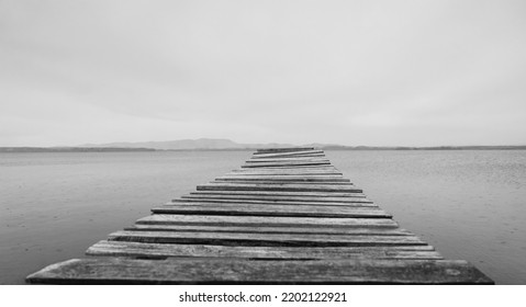 A Wooden Pontoon On A Dream Beach. South Ural, Russia. Pontoon Jetty Across The Water. Empty Summer Lake. Wooden Ponton On Water For Boat Fishing. No People. 