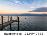 Wooden pontoon opening onto the snow-capped Alps on the shores of Lake Geneva in Morges at sunset (Canton of Vaud, Switzerland)