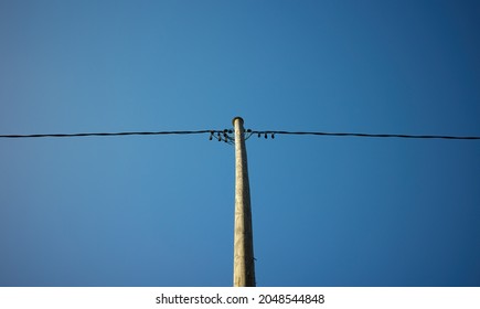 A Wooden Power Pole Against A Clear Blue Sky.