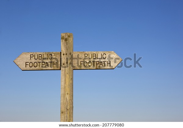 a\
wooden public footpath sign on a blue sky\
background
