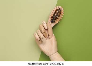 Wooden Puppet Hand Holding Eco Bamboo Hair Brush On Green Background