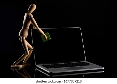 Wooden puppet imitating dusting laptop on black background - Powered by Shutterstock