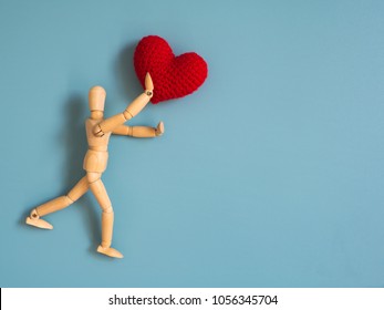 Wooden puppet jumping from the wooden floor in the air to catch the red heart floating in the sky. Wooden puppet try to jump to catch love. Concept of effort and love - Powered by Shutterstock