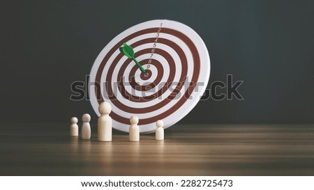 A wooden puppet with a red arrow pinned in the center of the target. Concepts, business goals, competitions, ambitions, dreams and themes are the heart of business.