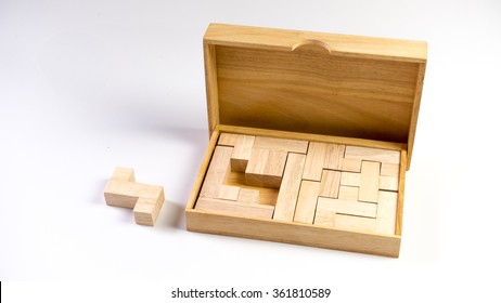 Wooden puzzle box with missing pieces outside the box. Isolated on white background. Slightly de-focused and close-up shot. Copy space.