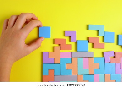 wooden puzzle game in the form of puzzles of different colors on a yellow background close-up selective focus.