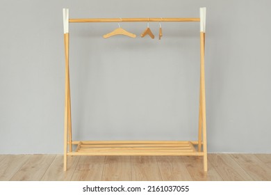 Wooden rack with hangers near grey wall