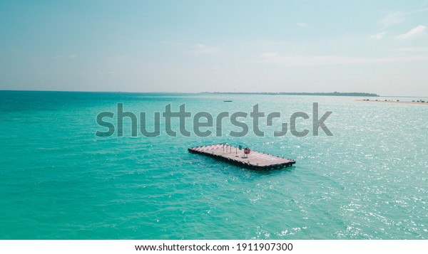 A wooden\
raft in a turquoise lake in the\
Maldives