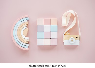 Wooden Rainbow, Colorful Blocks And Toy Camera. Stylish Baby Toys On Pastel Pink Background. Eco Friendly, Plastic Free Toys Accessories For Kids. Flat Lay, Top View