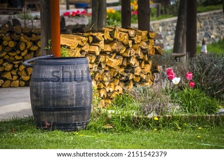 Wooden rainwater barrel, chopped wood in the background