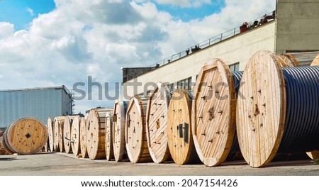 Wooden reels with electrical power cables at stand in row in the warehouse. Wire on wooden coils. Electrical power wire equipment