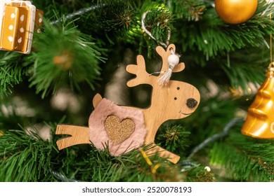  Wooden reindeer ornament with heart detail hanging from the branch of a Christmas tree, capturing the warmth of holiday decorations. High quality photo - Powered by Shutterstock