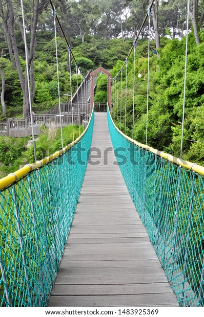 Wooden rope\
bridge in the park. Outdoor wood\
bridge.