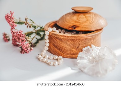 Wooden round box with pearls on a light background