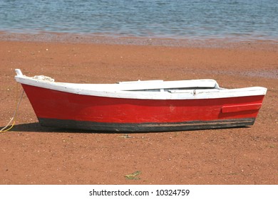 A wooden row boat on the beach at low tide.